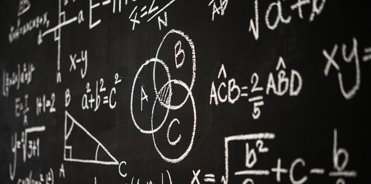 Blackboard inscribed with scientific formulas and calculations in physics, mathematics and electrical circuits. Science and education background.