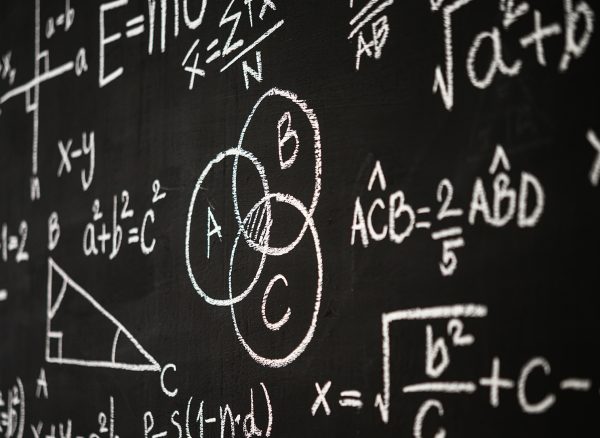 Blackboard inscribed with scientific formulas and calculations i Blackboard inscribed with scientific formulas and calculations in physics, mathematics and electrical circuits. Science and education background.