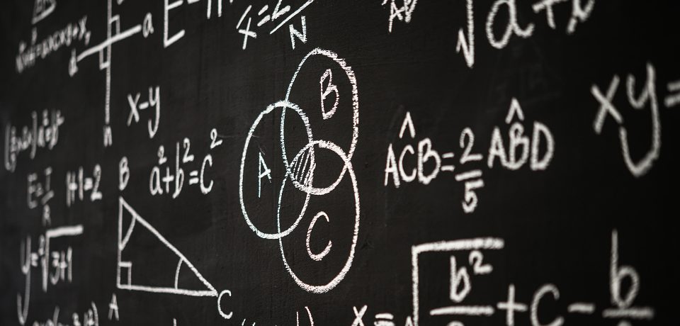 Blackboard inscribed with scientific formulas and calculations in physics, mathematics and electrical circuits. Science and education background.
